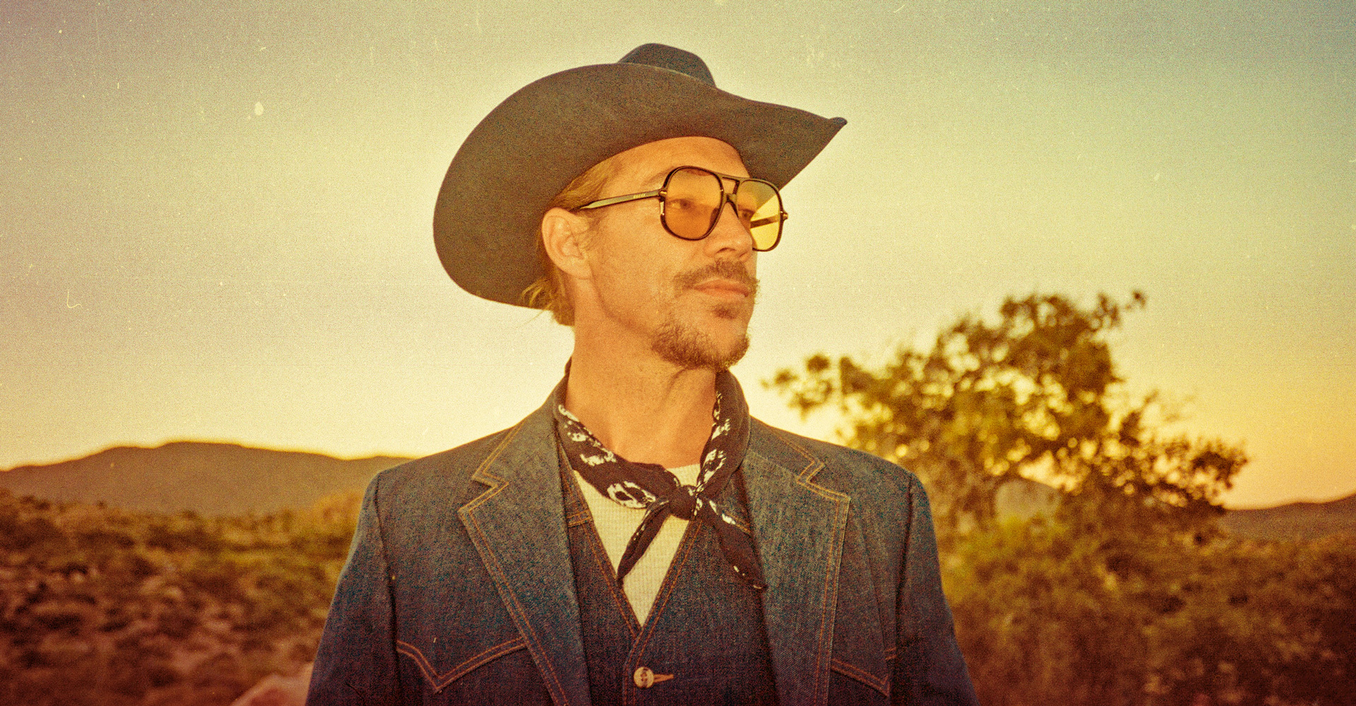 Diplo in cowboy hat and denim jacket in desert setting